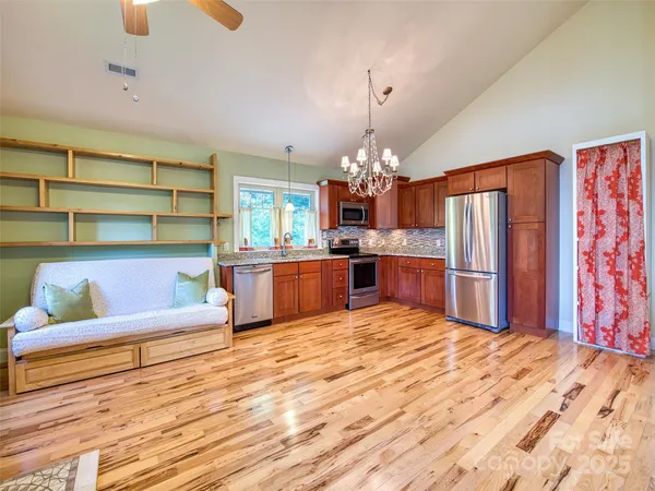 a large kitchen with stainless steel appliances kitchen island granite countertop a table chairs in it and a window