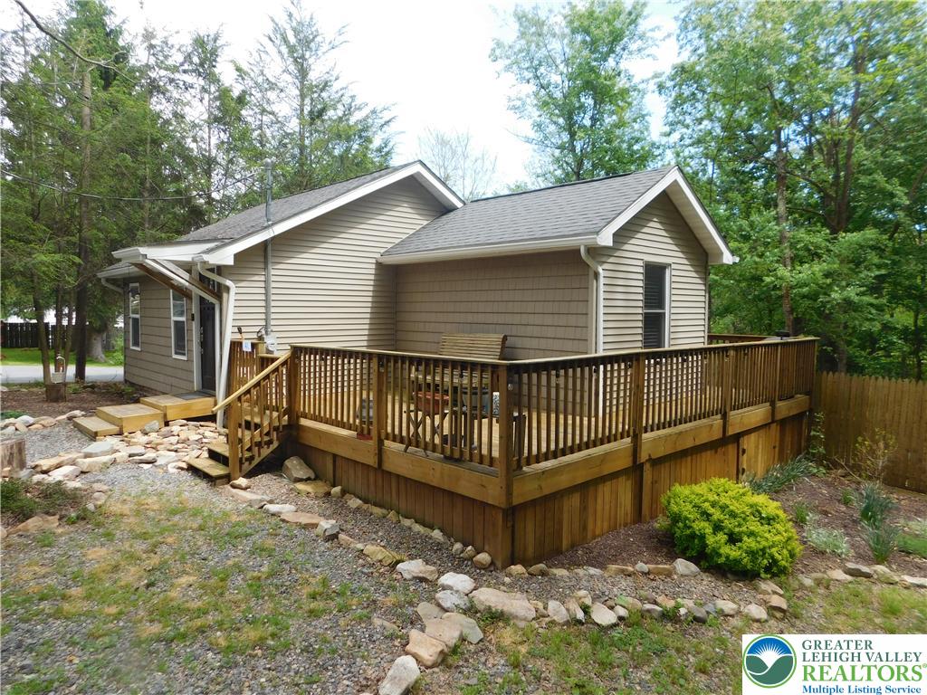 41 Reeder Street Mount Pocono, PA 18344 - Photo 5 of 41 A spacious wrap-around wooden deck extends from the residence, surrounded by mature trees and natural landscaping.