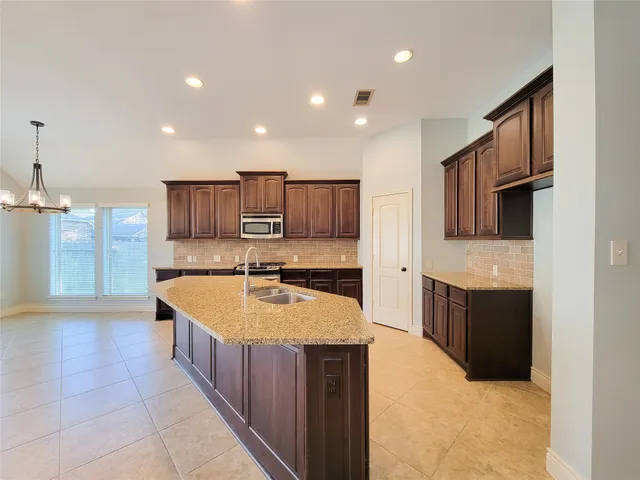 a large kitchen with stainless steel appliances kitchen island granite countertop a large counter top and wooden cabinets