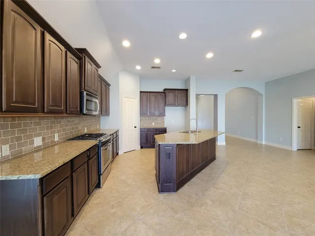 a large kitchen with stainless steel appliances kitchen island granite countertop a sink and cabinets