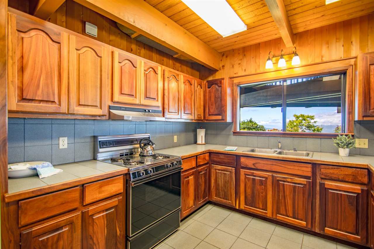 1470 Naalae Road Kula, HI 96790 - Photo 17 of 30 a kitchen with stainless steel appliances granite countertop a sink and wooden cabinets