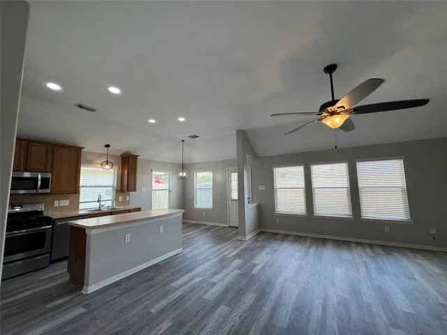 a kitchen with stainless steel appliances granite countertop a stove a sink and a microwave