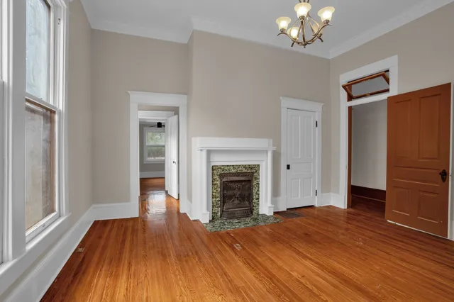 a view of an empty room with wooden floor fireplace and a window