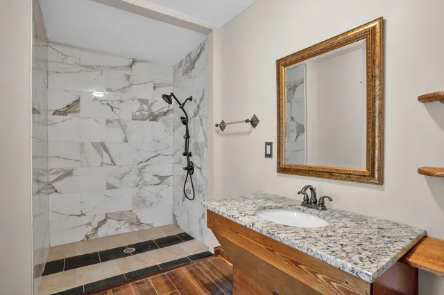 a bathroom with a granite countertop sink a mirror and shower
