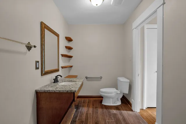 a bathroom with a granite countertop sink and a toilet