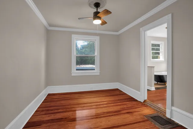 a view of empty room with wooden floor and fan