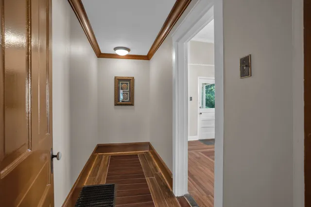 a view of a hallway with wooden floor and a bathroom