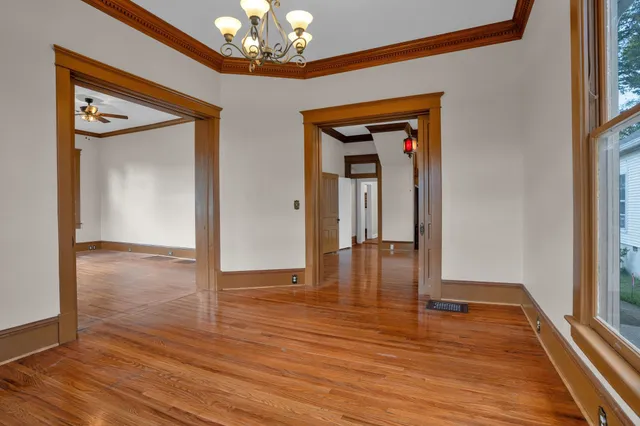 a view of a hallway with wooden floor and a chandelier