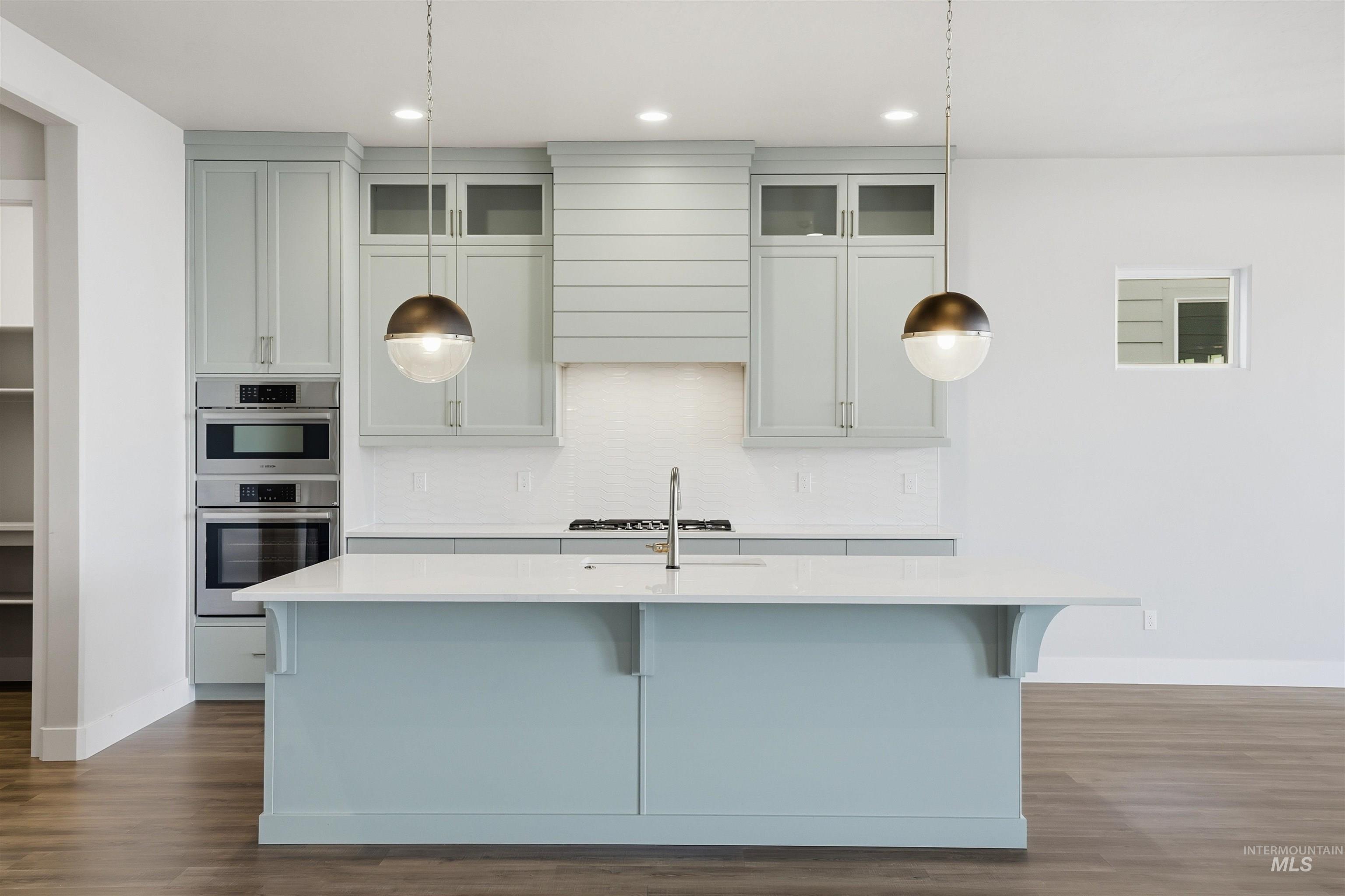 2976 East Parulo Drive Meridian, ID 83642 - Photo 11 of 40 Kitchen featuring glass insert cabinets, dark wood-style flooring, a kitchen bar, light stone countertops, and recessed lighting