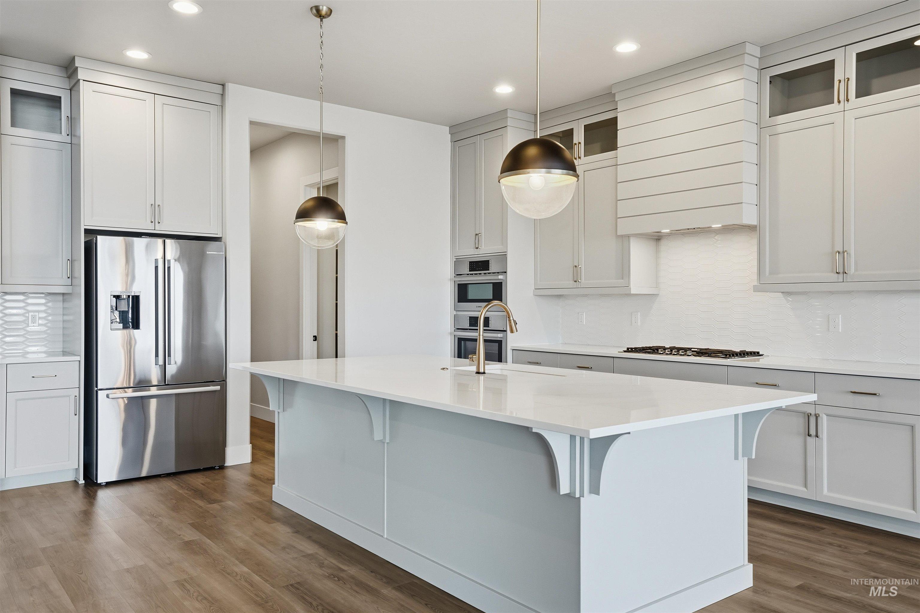 2976 East Parulo Drive Meridian, ID 83642 - Photo 12 of 40 Kitchen with backsplash, glass insert cabinets, appliances with stainless steel finishes, dark wood finished floors, and recessed lighting