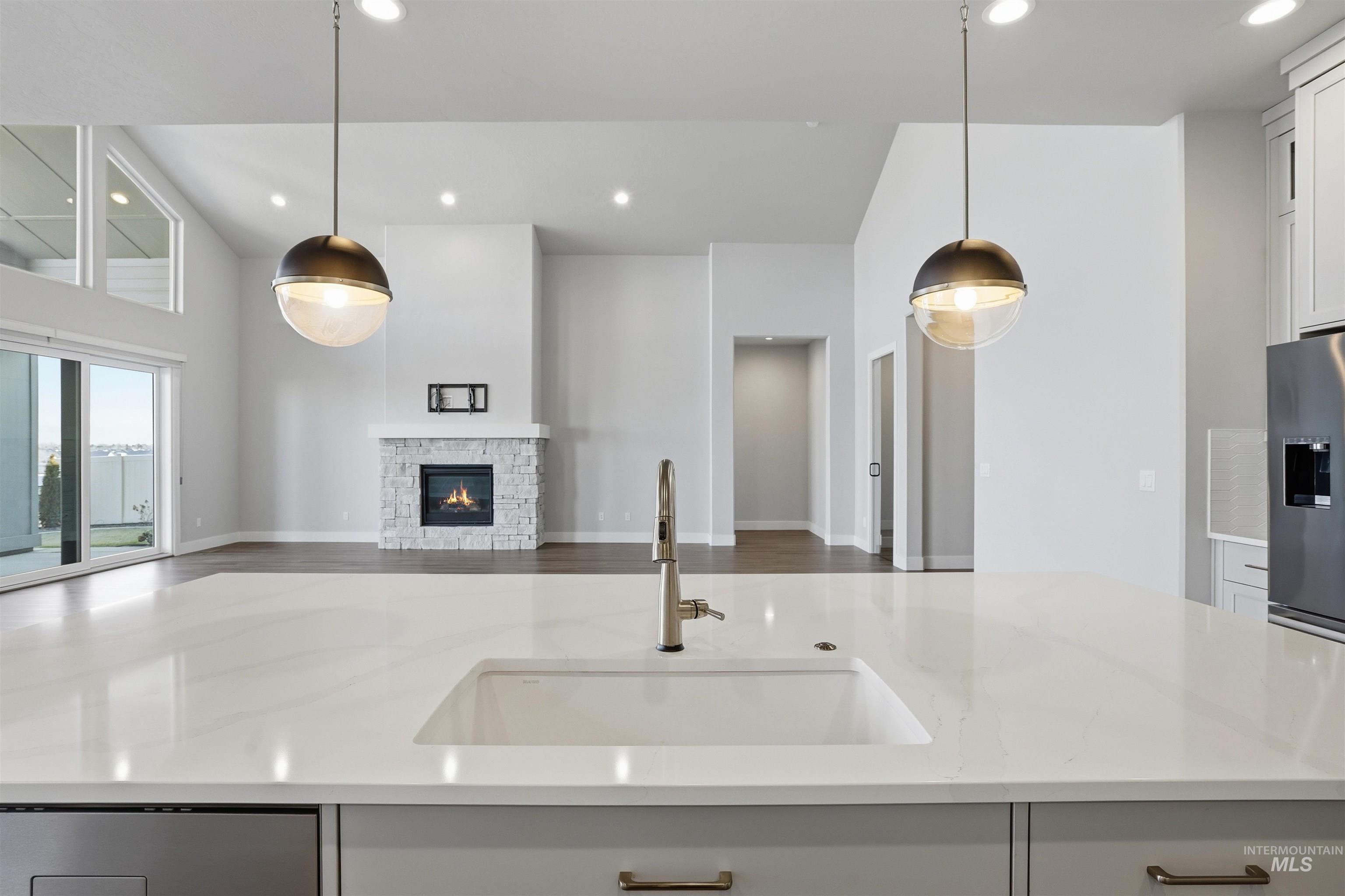 2976 East Parulo Drive Meridian, ID 83642 - Photo 40 of 40 Kitchen featuring light stone countertops, open floor plan, a fireplace, recessed lighting, and white cabinetry
