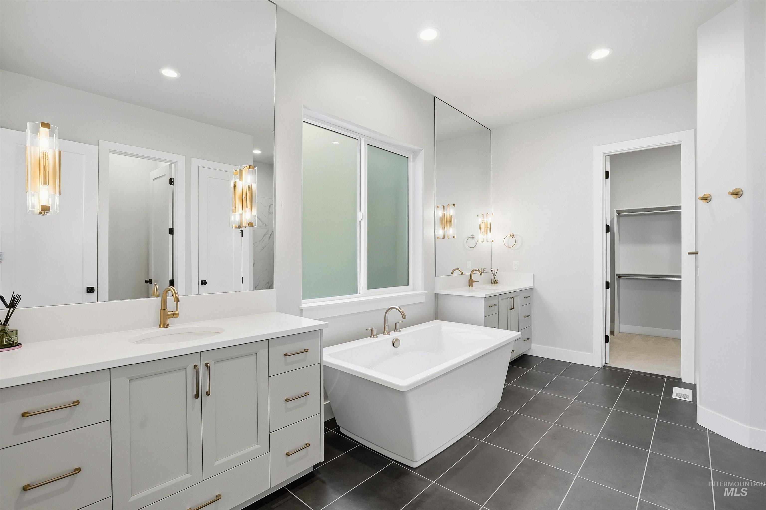 2976 East Parulo Drive Meridian, ID 83642 - Photo 20 of 40 Full bathroom with two vanities, a soaking tub, recessed lighting, dark tile patterned flooring, and a spacious closet