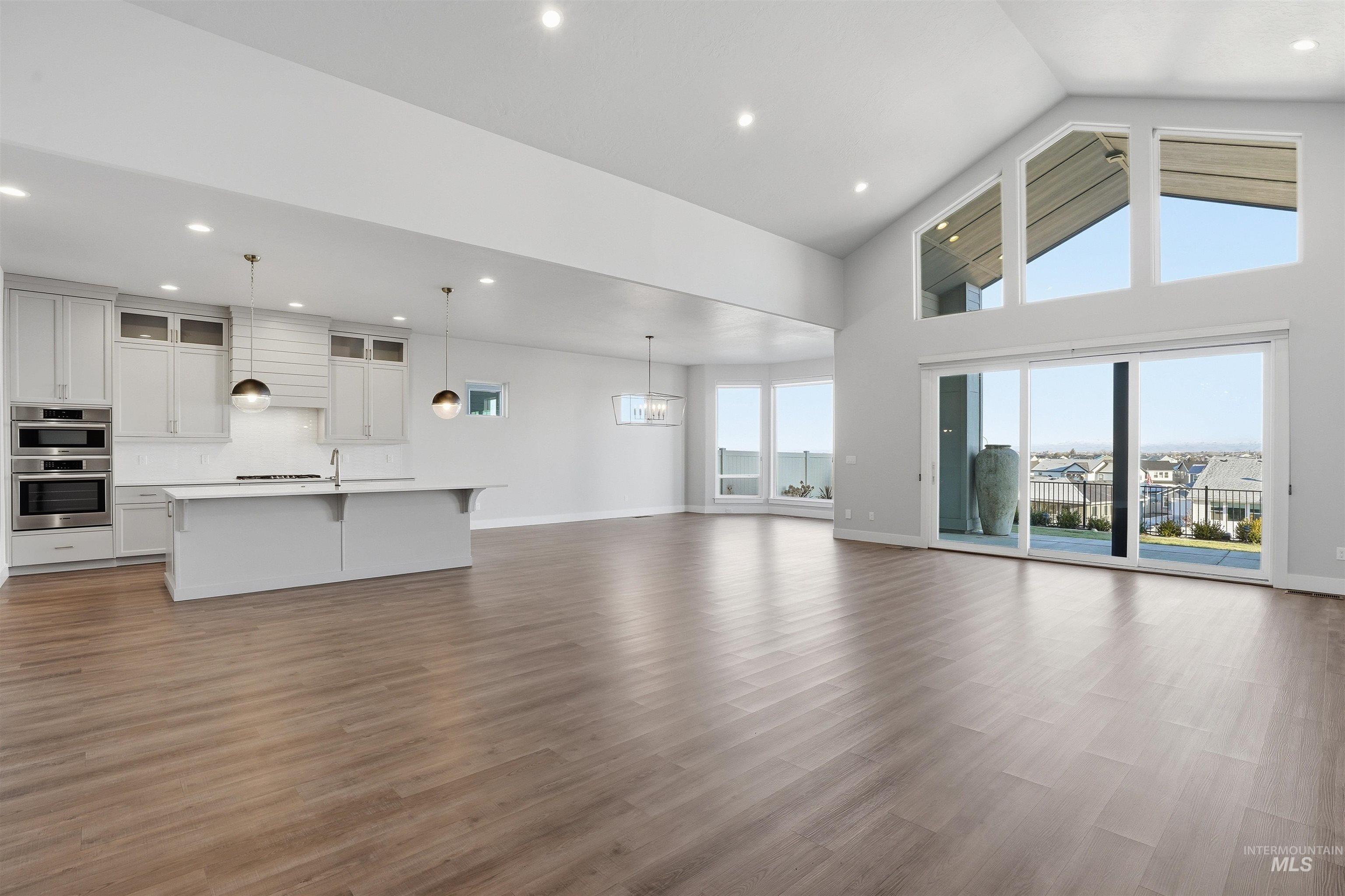 2976 East Parulo Drive Meridian, ID 83642 - Photo 6 of 40 Unfurnished living room featuring dark wood-style flooring, recessed lighting, and high vaulted ceiling