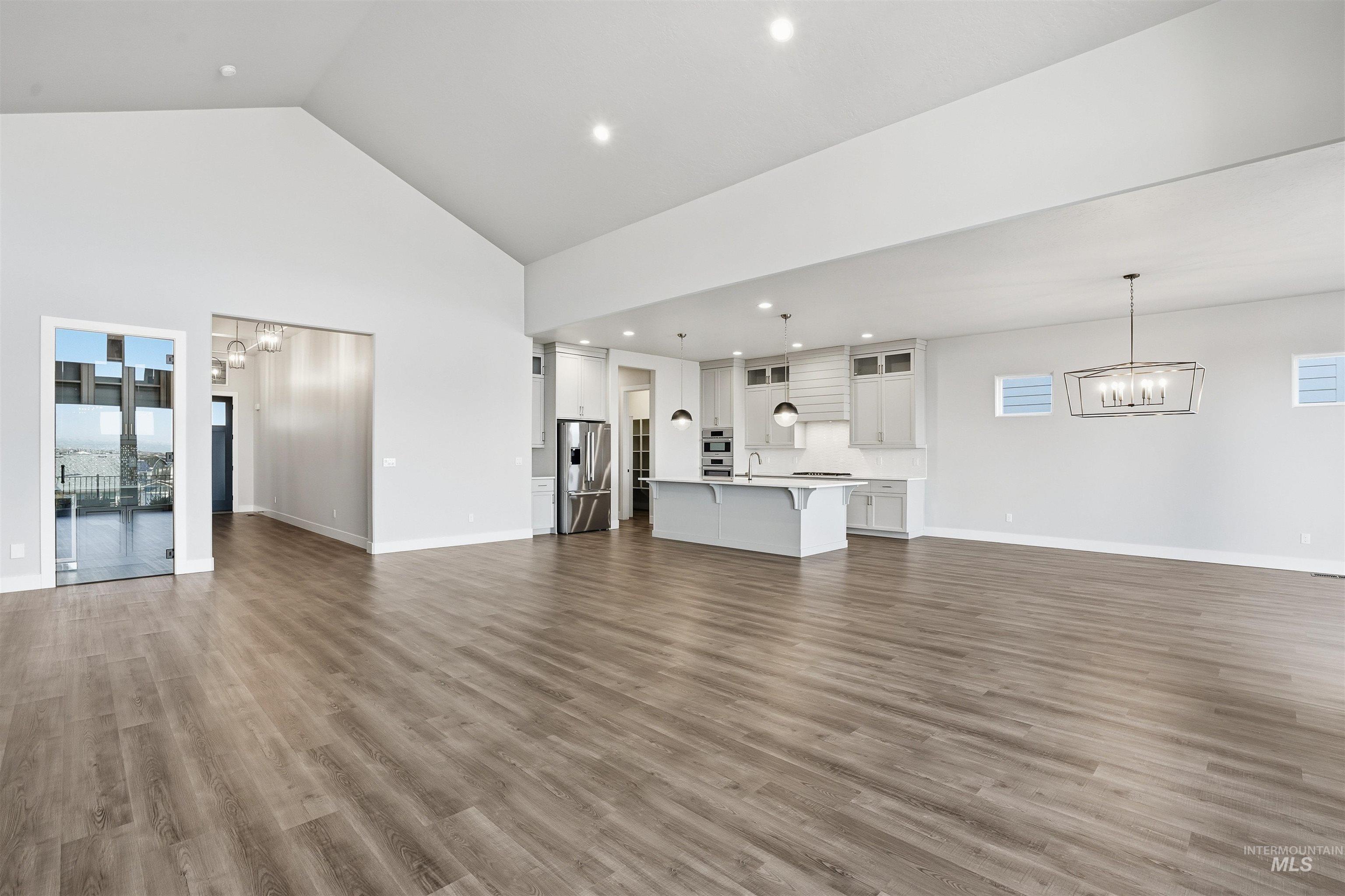 2976 East Parulo Drive Meridian, ID 83642 - Photo 7 of 40 Unfurnished living room with a chandelier, dark wood-style flooring, high vaulted ceiling, and recessed lighting