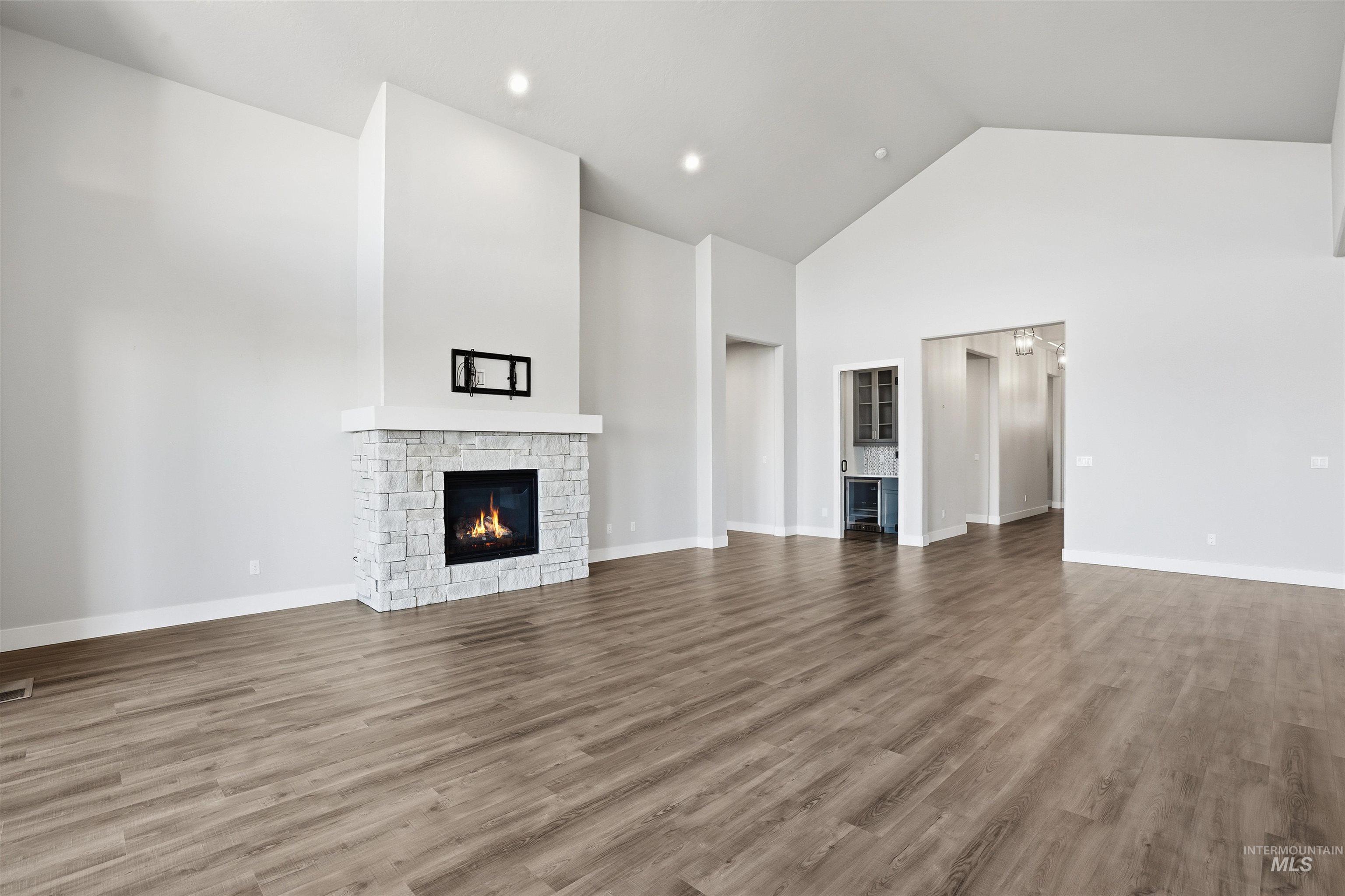 2976 East Parulo Drive Meridian, ID 83642 - Photo 8 of 40 Unfurnished living room featuring a stone fireplace, high vaulted ceiling, wood finished floors, and recessed lighting
