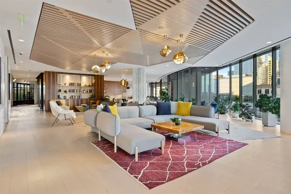 a living room with furniture a potted plant and kitchen view