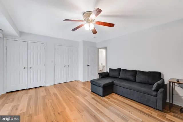 a living room with couches and ceiling fan with wooden floor