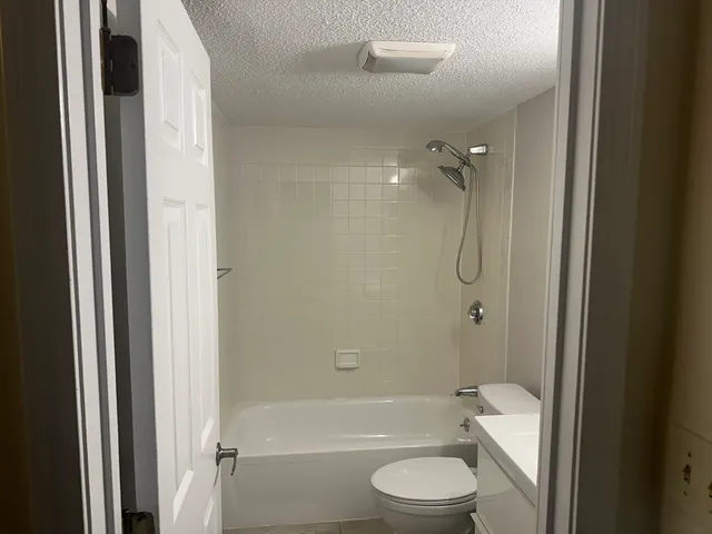 a bathroom with a granite countertop bathtub shower sink vanity and a toilet