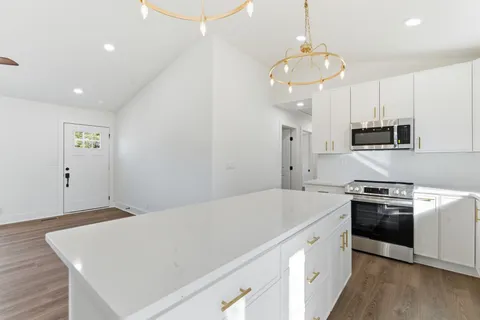 a kitchen with stainless steel appliances a white table chairs and a wooden floor