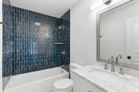 a bathroom with a granite countertop bathtub sink vanity mirror and toilet