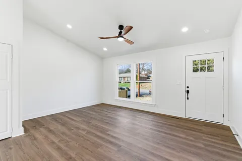 an empty room with wooden floor ceiling fan and windows