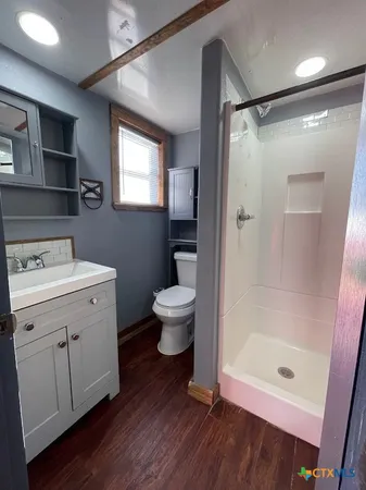 a bathroom with a shower sink vanity mirror and toilet