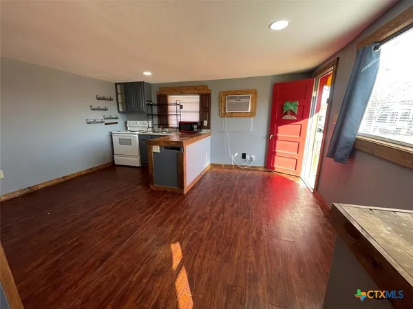 a kitchen with stainless steel appliances granite countertop a refrigerator a sink dishwasher a stove and white countertops with wooden floor