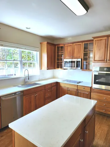 a kitchen with stainless steel appliances granite countertop a sink a stove and wooden cabinets