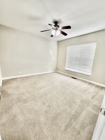 an empty room with windows and fan