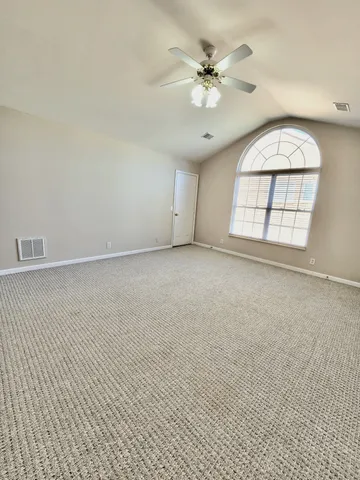 an empty room with windows and ceiling fan