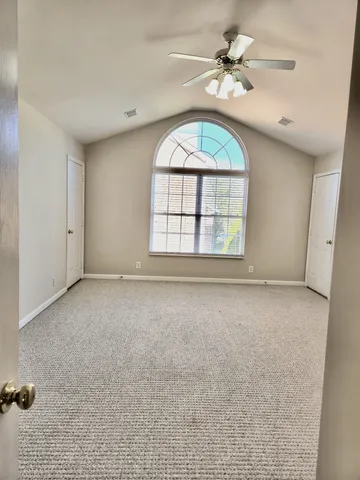 an empty room with windows and ceiling fan