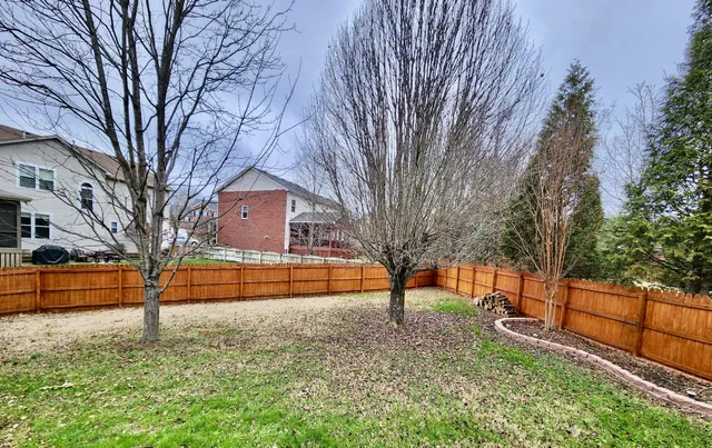 a view of a yard with a house and wooden fence