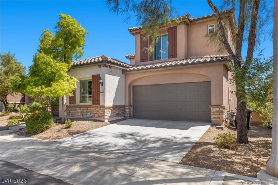 Daytime view of the two story front elevation, paver driveway, and three car tandem garage.