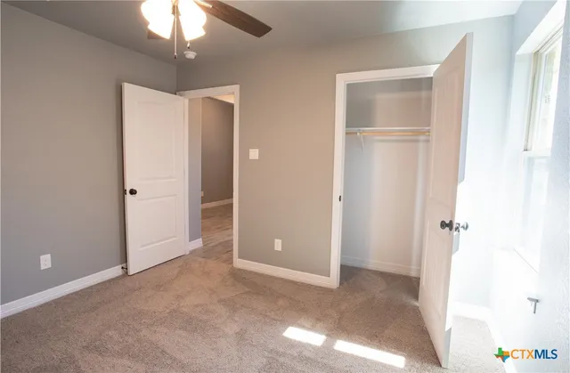 an empty room with closet and a chandelier fan