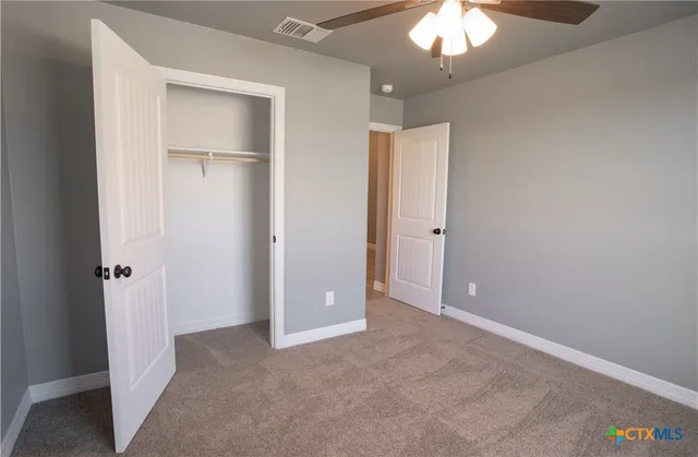 an empty room with closet and a chandelier fan