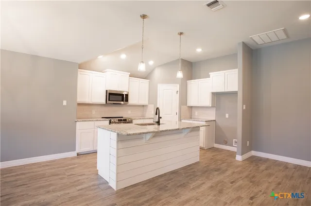 a kitchen with stainless steel appliances granite countertop a sink a stove and a refrigerator