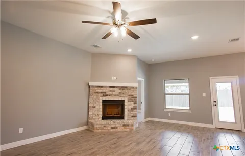 an empty room with wooden floor fireplace and windows