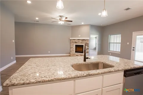 a kitchen with a sink granite counter tops and a fireplace