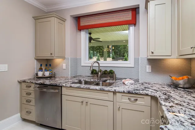 a kitchen with white cabinets and a window