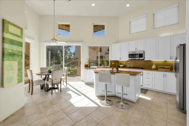 a kitchen with stainless steel appliances kitchen island granite countertop a stove a sink a dining table and chairs