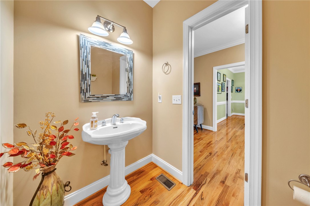 648 Mountain View Road Williamston, SC 29697 - Photo 16 of 42 A well-lit powder room offers a pedestal sink and rich hardwood flooring, leading to an inviting hallway.