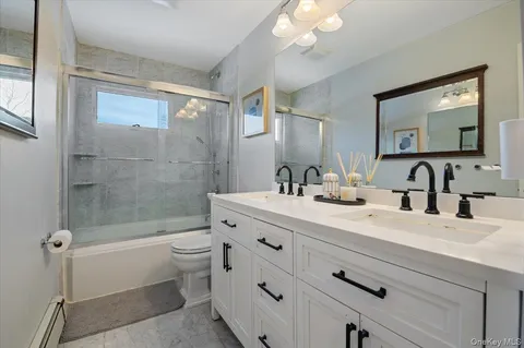 a bathroom with a double vanity sink toilet and shower