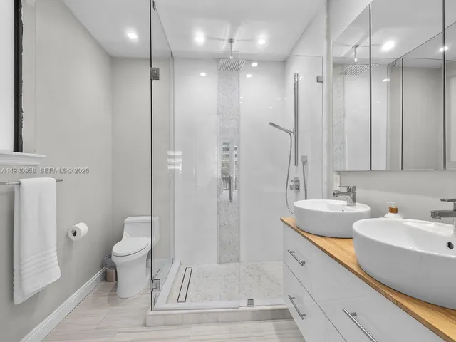 a bathroom with a sink a toilet a large mirror and shower