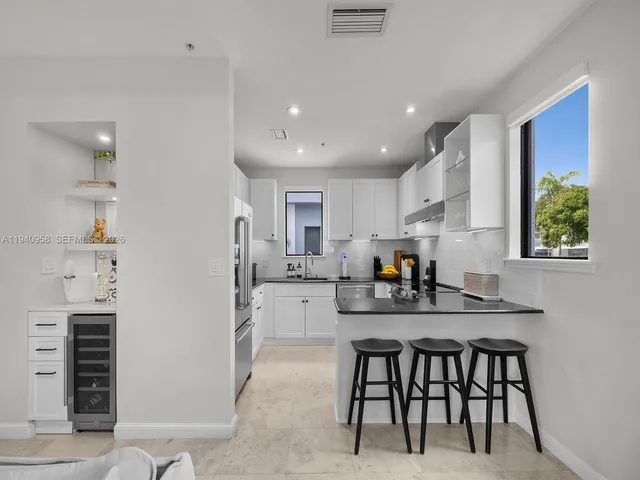 a kitchen with stainless steel appliances kitchen island granite countertop a dining table chairs and stove