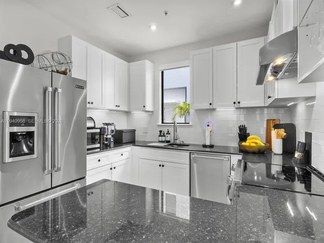 a kitchen with stainless steel appliances a stove a sink a refrigerator a counter space and cabinets