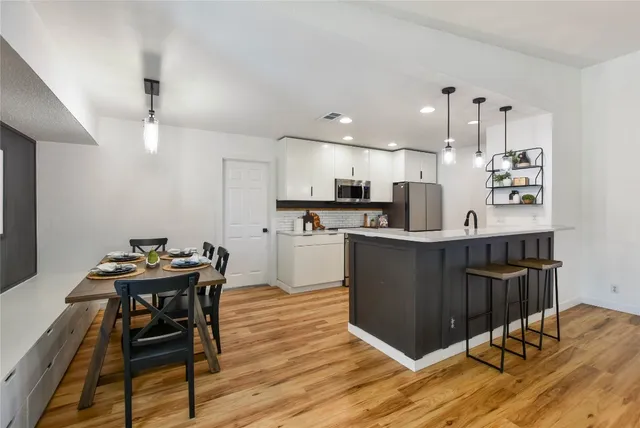 a living room with stainless steel appliances kitchen island granite countertop furniture wooden floor and a kitchen view