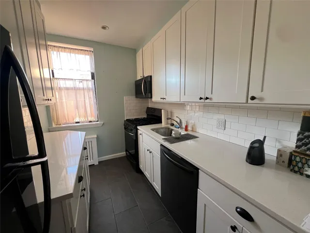 a kitchen with a sink a refrigerator a window and cabinets