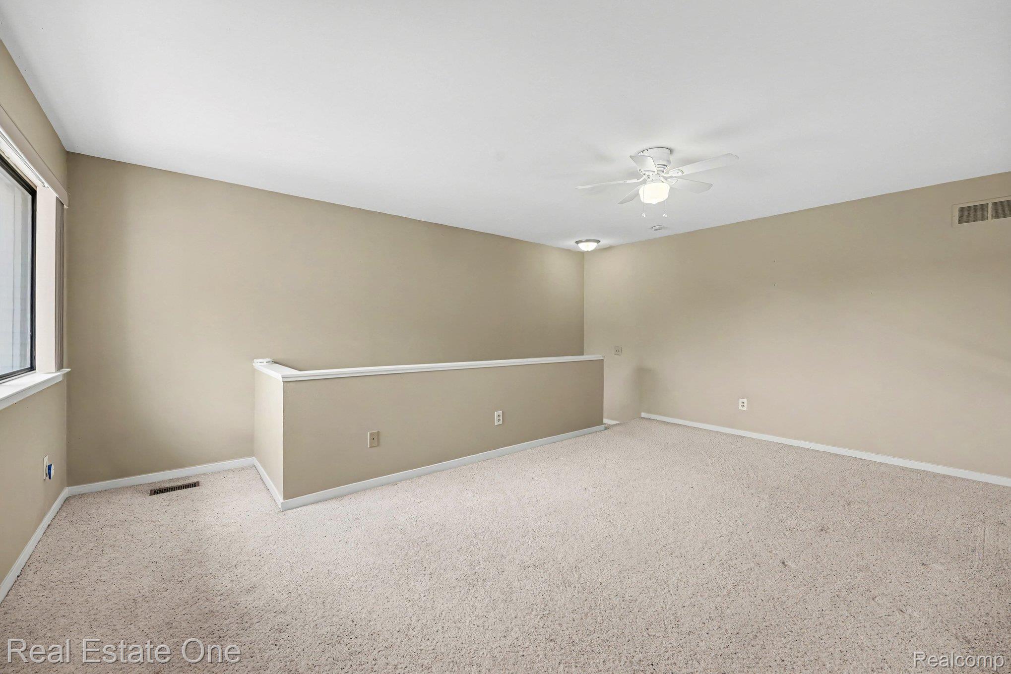 701 Charing Court Rochester, MI 48307 - Photo 19 of 29 Upper-level room featuring neutral-toned carpeting, a window providing natural light, a ceiling fan with integrated lighting, and a partial wall with a white cap