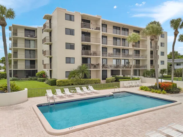 a view of a swimming pool with a lounge chairs in front of a house