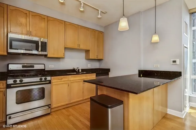 a kitchen with stainless steel appliances granite countertop a stove a sink and a microwave